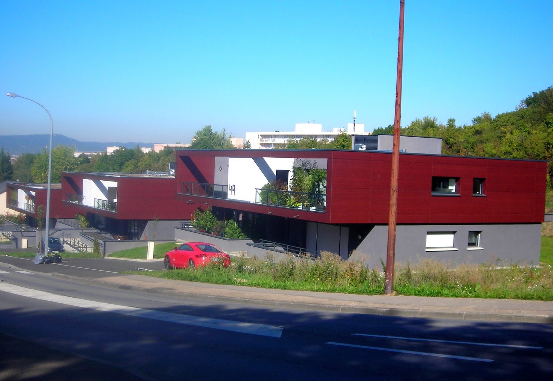 Résidence en bardage rouge et toits-terrasses